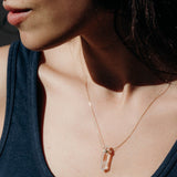 Close-up of a woman's décolletage wearing The Clarity Retreat Necklace, styled in a navy tank top.