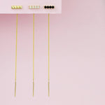 An Alli Webb Faceted Threader, Onyx Threader and Opal Threader against a light pink background. 