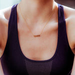 A close-up of a décolletage wearing a FEMME Necklace with a dark purple top. 
