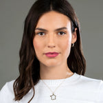 A brunette woman wearing a France necklace and a Tres Pearl Earring in yellow gold with a white knit against a grey background. 