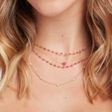 Close-up of a blonde woman's neck wearing a yellow gold Quintet Diamond Layering Necklace, The Sweetheart Necklace - Pink Sapphire and The Peony Bouquet Necklace. 