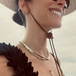 Abigail Spencer wearing a yellow gold Bold Link Chain, Sequence Chain and two Retreat Necklaces in Clarity and Love,  with a straw hat, sunglasses and a black top with a white blurred background. 