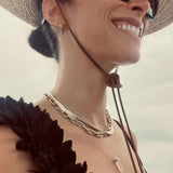 Abigail Spencer wearing a yellow gold Bold Link Chain, Sequence Chain and two Retreat Necklaces in Clarity and Love,  with a straw hat, sunglasses and a black top with a white blurred background. 