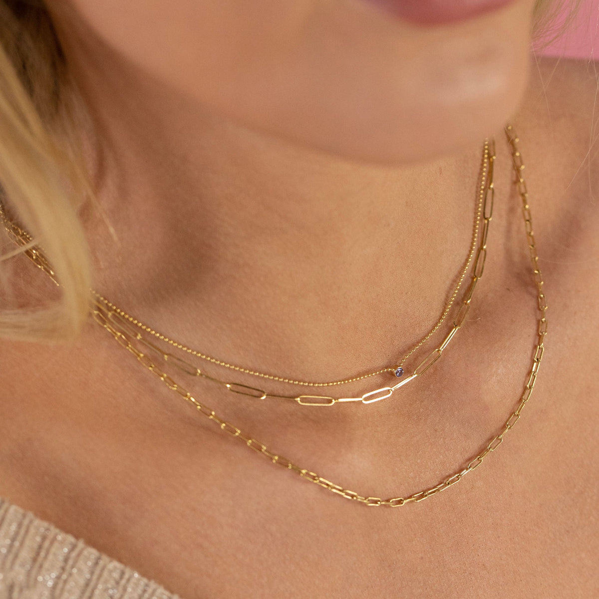 Close-up of a person's neck wearing a Single Birthstone Layering Necklace - Yellow Gold, an Element Long Link Chain and an Element Short Link Chain, all in yellow gold.  