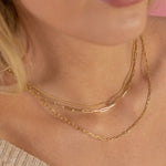 Close-up of a person's neck wearing a Single Birthstone Layering Necklace - Yellow Gold, an Element Long Link Chain and an Element Short Link Chain, all in yellow gold.  