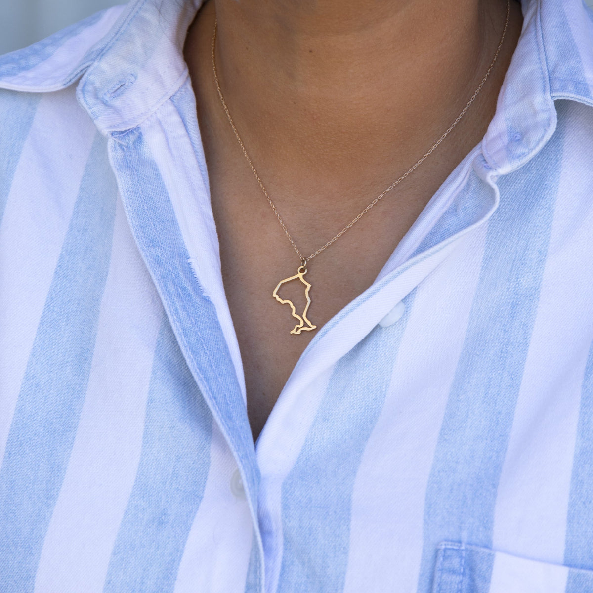 Close-up of a person's neck wearing an Ontario necklace in yellow gold with a blue and white striped shirt against a light grey blurred background.