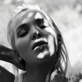 Black and white photo of a woman wearing an Open Eclipse Earring - Small with sunlight casting shadows on her face. 