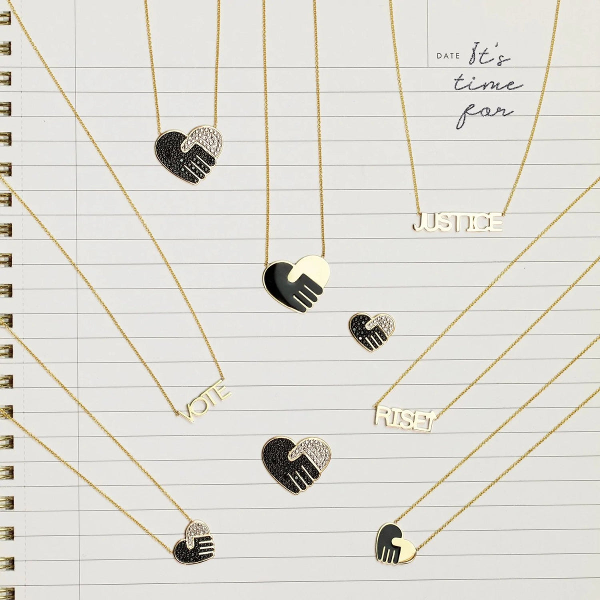 Pavé Unity Pendants - Large and Small, an Enamel Gold Unity Pendant - Small, an Enamel Gold Unity Pendant - Large, VOTE Necklace, JUSTICE Necklace and RiseUP Necklace, all in yellow gold, with a lined notepad page as the background. 