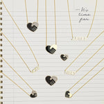 Pavé Unity Pendants - Large and Small, an Enamel Gold Unity Pendant - Small, an Enamel Gold Unity Pendant - Large, VOTE Necklace, JUSTICE Necklace and RiseUP Necklace, all in yellow gold, with a lined notepad page as the background. 