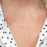 Close-up of a décolletage wearing a Pavé MIMI Necklace in yellow gold on a cable chain, with a black and white polka dot blouse. 