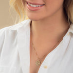 Close-up of a blonde woman wearing a Zodiac Necklace - Pisces with a white shirt against a neutral background. 