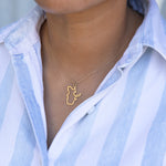 Close-up of a person's neck wearing a Quebec necklace in yellow gold with a blue and white striped shirt against a light grey blurred background.