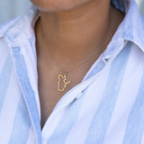 Close-up of a person's neck wearing a Quebec necklace in yellow gold with a blue and white striped shirt against a light grey blurred background.
