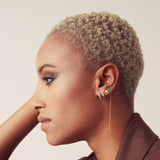 An Alli Webb Turquoise Huggie, Faceted Huggie, Opal Comfort Stud and Turquoise Threader worn by a woman with short blonde hair and a brown top against a light background. 