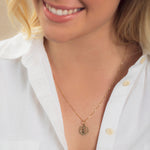 Close-up of a blonde woman wearing a Zodiac Necklace - Virgo with a white shirt against a neutral background. 