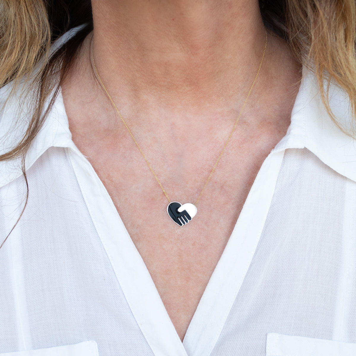 Close-up of a woman's decellotage wearing an Enamel Gold Unity Pendant - Large with a white shirt. 