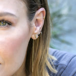 Close-up of a woman's ear wearing an Alli Webb Faceted Threader, Onyx Comfort Stud and Onyx Huggie with an outdoors blurred background. 